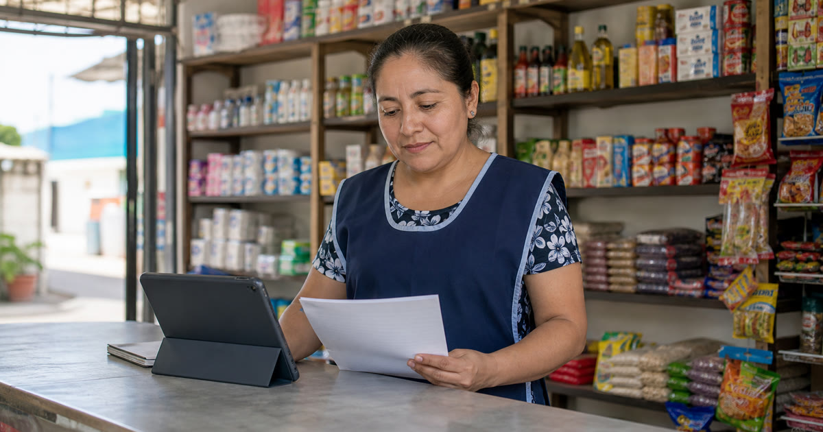 Dueña de una miscelánea comparando opciones de punto de venta junto al mostrador y productos acomodados